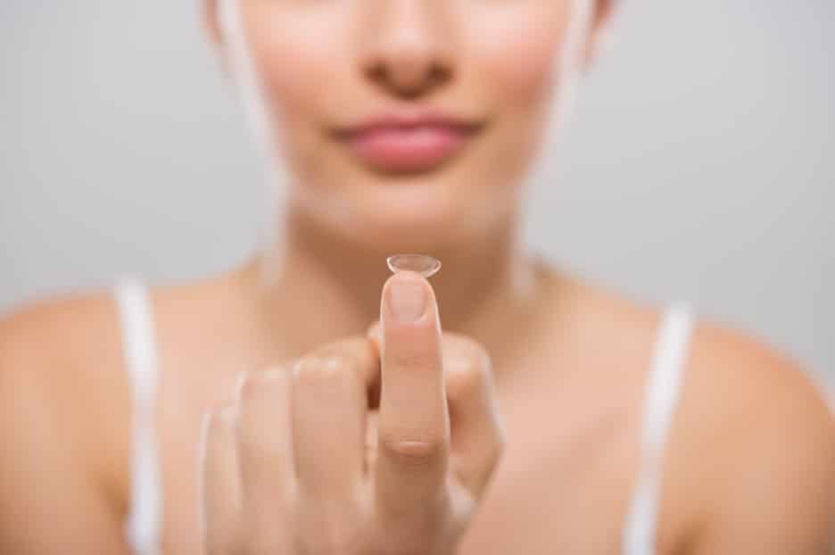 woman holding a contact lens on the tip of her finger
